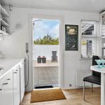 Küche mit Essbereich, Balkon und Fenster. Weiße Schränke und Holzboden.