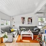 Wohnzimmer mit grauem Sofa, weißem Tisch und orangefarbenem Teppich