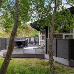 Deck with table and chairs surrounded by trees and grass.