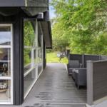 Deck with seating and view into the house. Surrounded by trees and greenery.