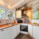 Kitchen with wooden surfaces, white cabinets, and windows overlooking trees.