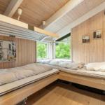 Two sleeping areas with mattresses and bedding against wooden walls and ceiling. Windows with view of greenery.