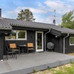 A house with a terrace, table, chairs, and grill. Surrounded by trees and grass.