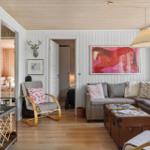 Wohnzimmer mit Sofa, Kamin und Wandbildern. Durchgänge zu Schlafzimmern.