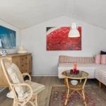 Wohnraum mit Sofa, Stuhl, Tisch und Wandbildern.