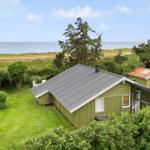 Grünes Ferienhaus mit Garten und Meerblick. Terrasse und Liegestühle im Freien.