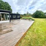 Holzterrasse neben modernem Haus mit Garten und Schaukel.