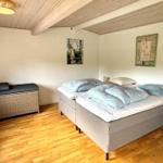 Schlafzimmer mit Bett, Holzboden und Deckenbalken. Wandbild und Kissen sind sichtbar.