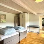 Zwei Betten, Schrank und Tisch in einem Raum mit Holzboden und Decke.