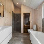 Bathroom with bathtub, toilet, shower, and sink. Wooden walls and window with sky view.