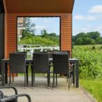 Terrace with dining table and chairs. View of green landscape and sky.