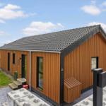 Modern wooden cabin with roof and windows. Lawn and driveway.
