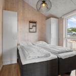 Room with two beds, wooden walls, and window view of the garden.