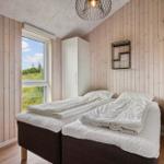 Two beds with white bedding, wooden walls, and window with view of grass.