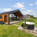 Modern wooden cabin with terrace and hot tub in grassland