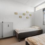 Zimmer mit zwei Betten, Fenster und Heizkörper an der Wand.
