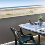 Terrasse mit Tisch und Stühlen, Blick auf Strand und Meer.