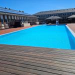 Ein klarer Swimmingpool mit Holzterrasse und modernen Gebäuden im Hintergrund.