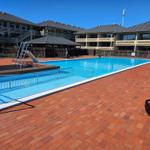 Pool mit Rutsche und Terrasse umgeben von mehrstöckigen Gebäuden.