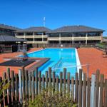 Pool mit Holzumrandung und mehrstöckigem Gebäude im Hintergrund.