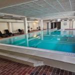 Innenpool mit Liegestühlen und Treppen zur Schwimmfläche.