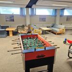 Spielzimmer mit Tischfußball, Sofas und Kinderspielzeug.