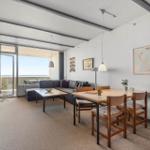 Wohn- und Essbereich mit Balkon, Sofa, Tisch und Stühle. Wandkarte und Pflanzen.