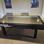 Ein Air-Hockey-Tisch mit zwei gelben Stöcken und einem orangefarbenen Diskett.