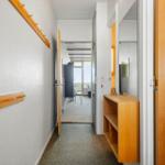 Flur mit Kleiderhaken, Spiegelschrank und Blick in Wohnbereich.