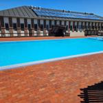 Pool mit rotem Pflaster und Gebäude mit Solarpaneelen auf Dach