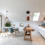 Küche mit Essbereich, Holzwerkbank und Dachfenstern. Tische und Stühle sind sichtbar.