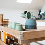 Holzblocktisch mit Küchenutensilien und grünen Dosen in der Küche