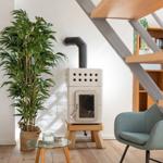Wohnraum mit Holzstufen, Pflanze, Ofen und Sitzgelegenheiten.