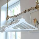 Haken an einem Ast hängen an einem Seil. Ein Bild eines Vogels an der Wand.