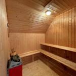 Sauna mit Holzwandverkleidung und Sitzbänken. Heizung mit Steinen.
