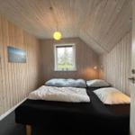 Schlafzimmer mit Holzwand, Bett, Fenster und Deckenleuchte.