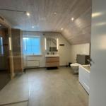 Moderne Badezimmer mit Dusche, Badewanne, Waschbecken und Toilette unter Holzdecke.