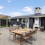 Hinterhof mit Tisch, Stühlen und Grill. Schwarze Holzwände und Pflanzen.