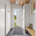 Eingangsbereich mit weißer Tür, Holzdecke und Schuhschrank. Durchgang zur Außentür.