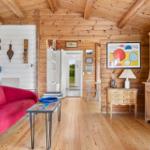 Ein Wohnzimmer mit Holzdecke, rotem Sofa und Holzmöbeln.