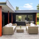 Deck with wicker sofa, table, and chairs. Black facade with red pillars.