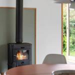 Wood stove with burning fire in a room with window and table