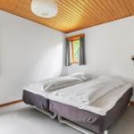 Two sleeping areas with bedding, wooden ceiling, and windows with curtains.