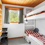 A bedroom with a bunk bed, a window, and a wooden shelf.