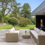 Deck with seating, grill and garden. Wooden floor, trees and grass visible.