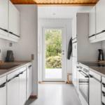 Kitchen with white cabinets, dark handles, and view to an outdoor area.