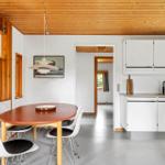 Kitchen and dining area with wooden ceiling, white built-in kitchen, and round table with chairs.