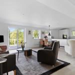 Living and dining area with kitchen, seating, and view to balcony.
