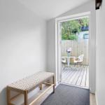 Entrance area with bench and door to balcony with table and chairs.