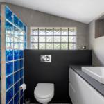 Bathroom with blue glass blocks, toilet, and sink with mirror.